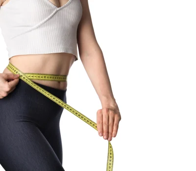 Woman using a measuring tape to track waist measurements